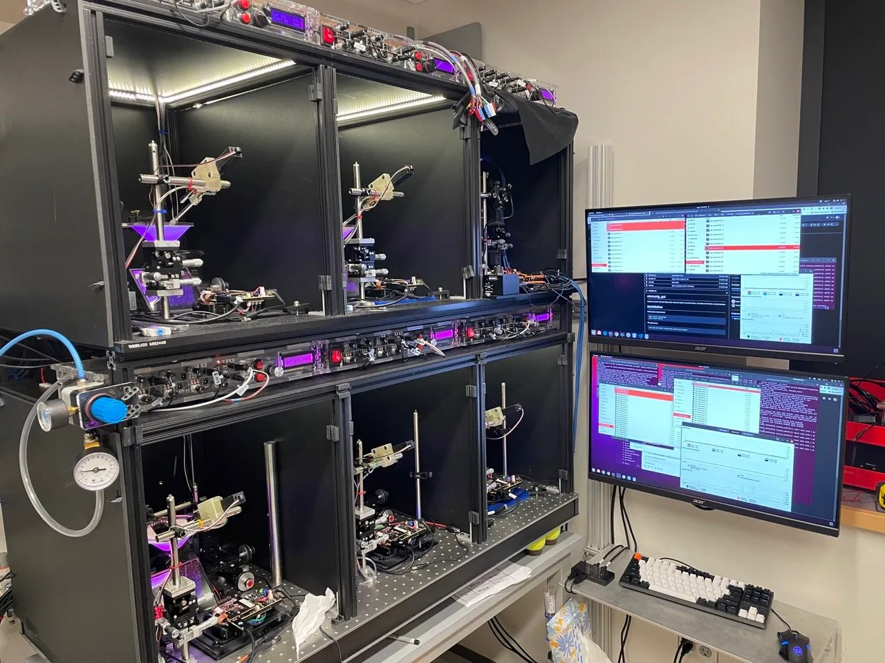 Six behavior rigs installed in a two-level enclosure beside monitors